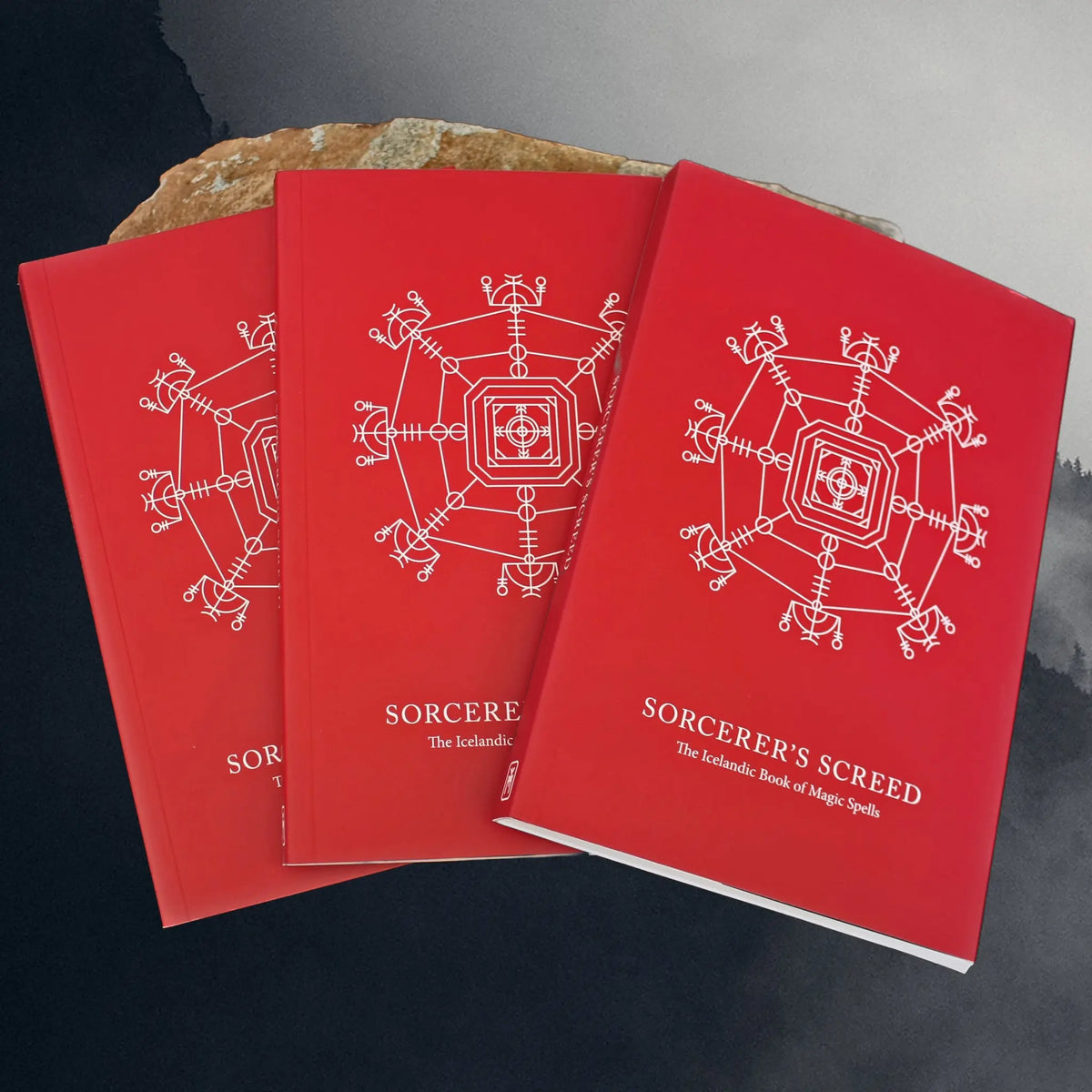 Sorcerer's Screed - The Icelandic Book of Magic Spells - Display of 3 Books on Rock
