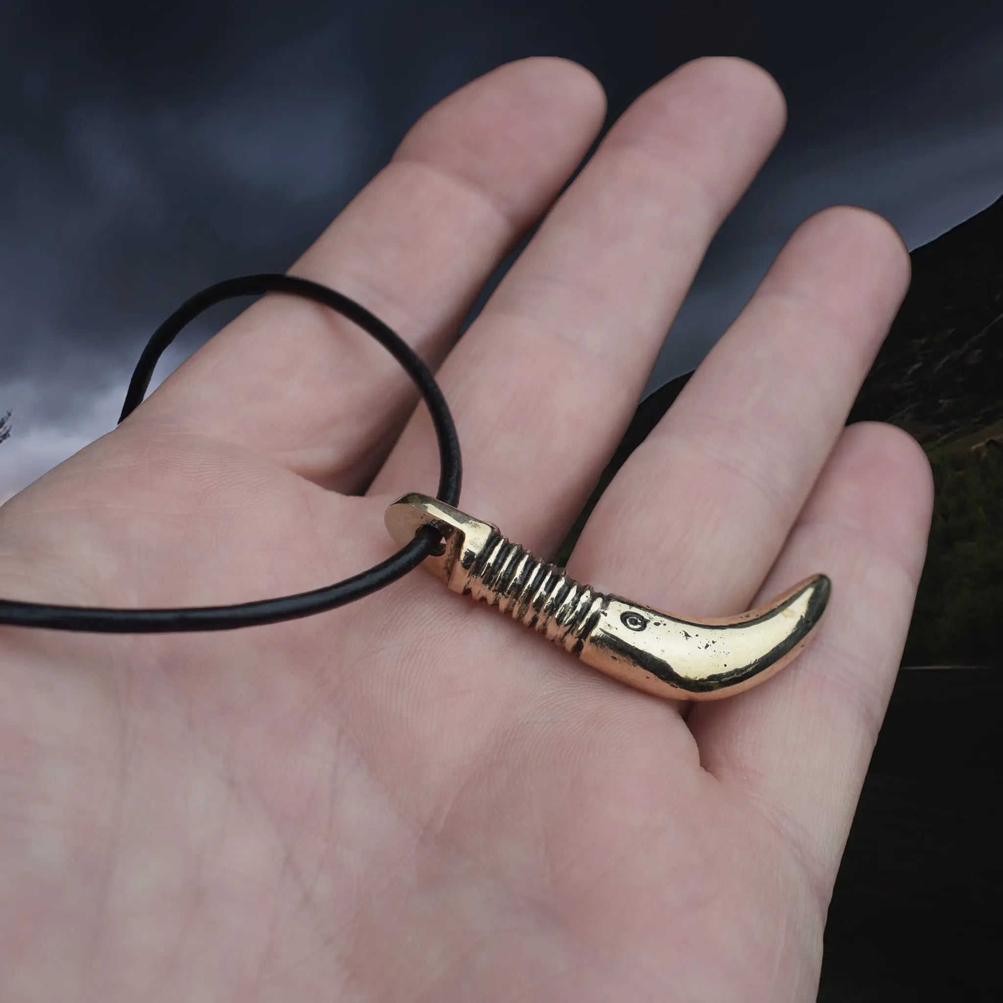 Solid Bronze Replica Viking Bear Tooth Pendant from 9th to 11th century Finland on Leather Cord, on Hand - Side Angle View